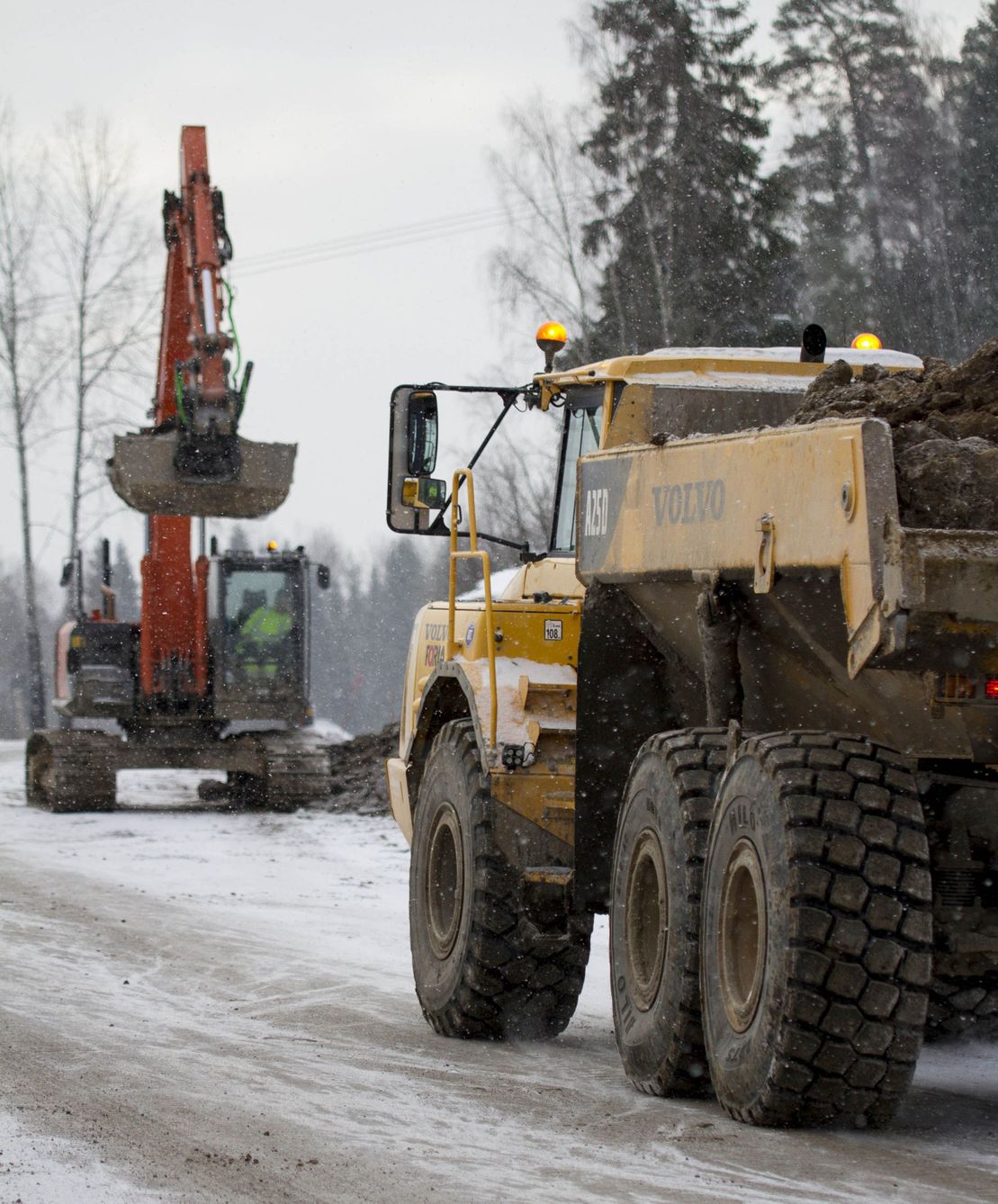 Grävmaskin och dumper i vinterväder